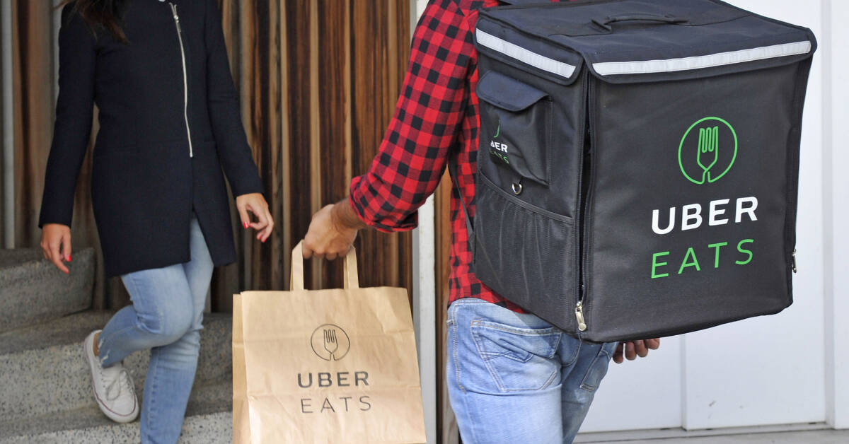 A man with an uber eats backpack and a shopping bag, delivering to hotel rooms.