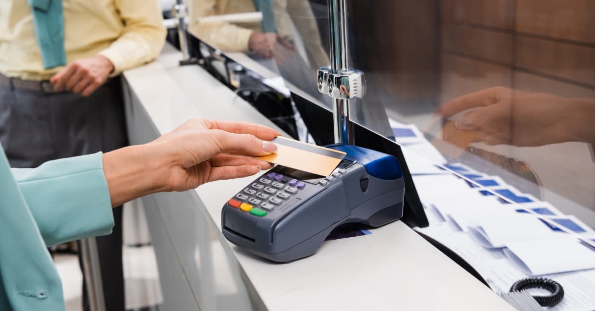 A person is paying a hotel deposit using a credit card at a hotel reception.