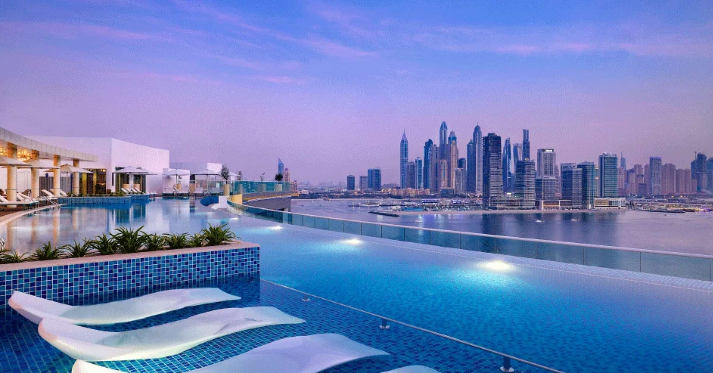 A swimming pool with lounge chairs and a view of the city in Dubai hotels.