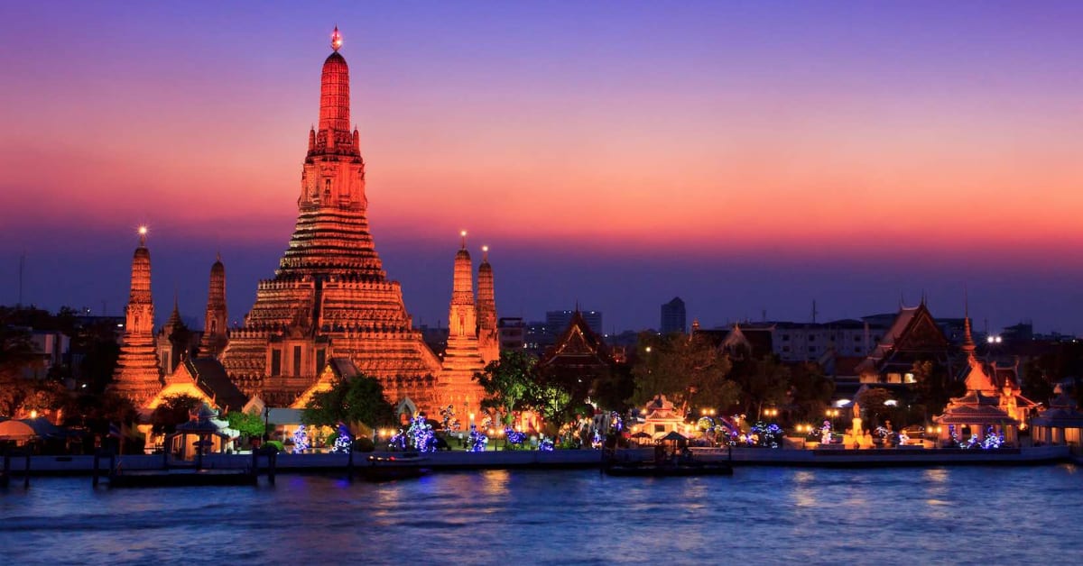 A large building with wat arun and a body of water located near Bangkok Hotels.